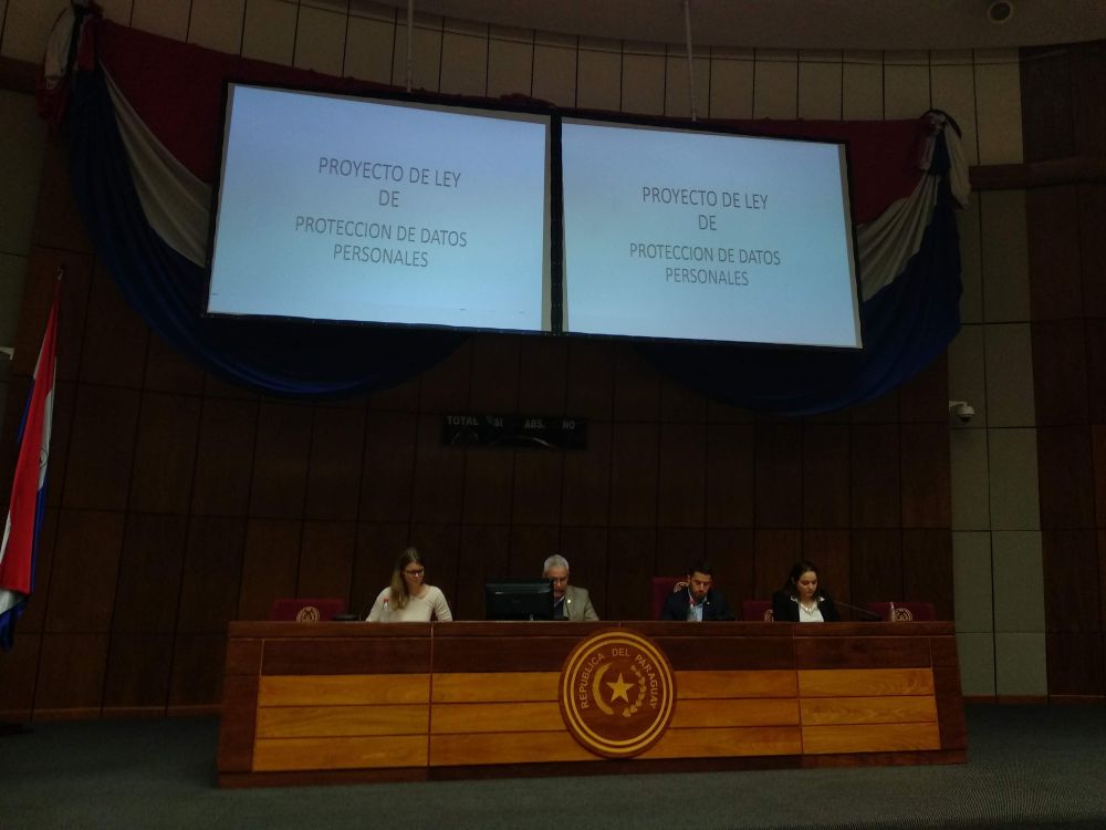 una mujer y tres hombres sentados en el estrado de la cámara de senadores