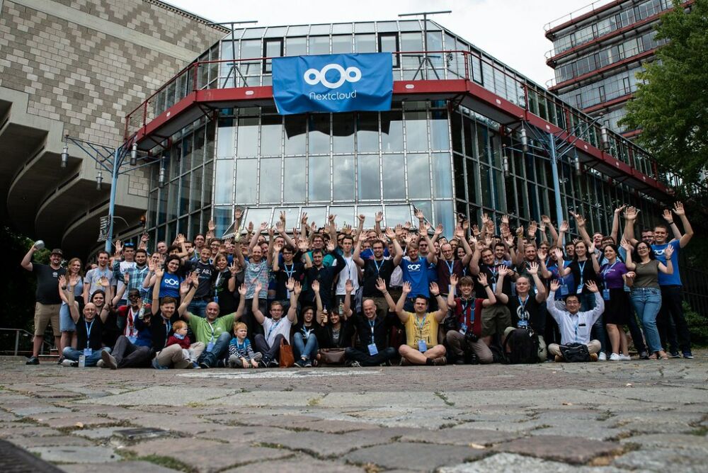 Gente posando en la calle con una bandera de Nextcloud de fondo